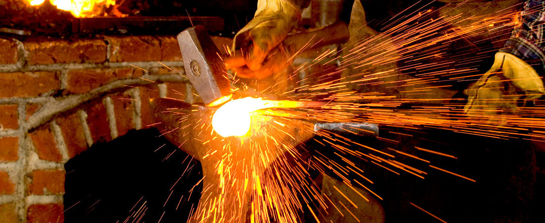 Site logo - a blacksmith strikes hot metal on an anvil, sending sparks and welding flux flying